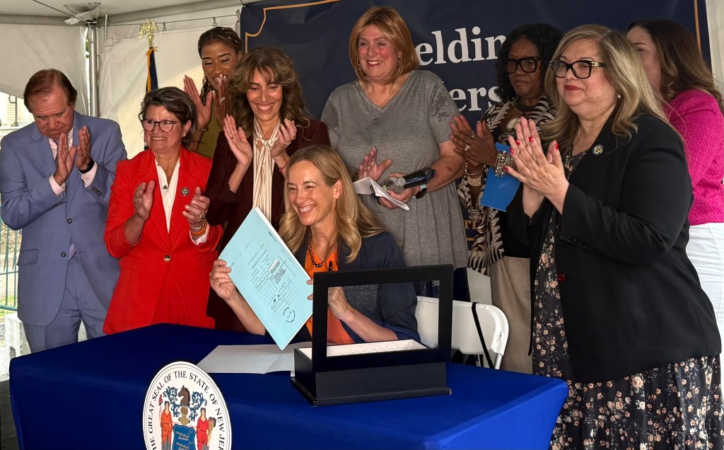 Gov. Mikie Sherrill, joined by political and legislative advocates, signs a reproductive and gender-affirming health care measure into law in Montclair on Thursday. Photo credit: Gianna Puglisi/NJ State House News Service