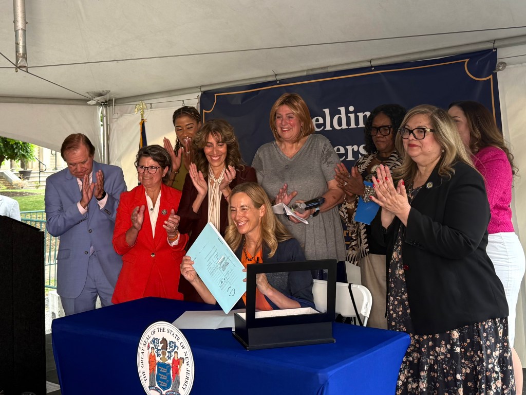 Assembly Member Luanne Peterpaul (wearing red), a Democrat from Long Branch, championed a reproductive and gender-affirming rights bill signed this summer by Gov. Mikie Sherrill. Photo credit: Gianna Puglisi/NJ State House News Service
